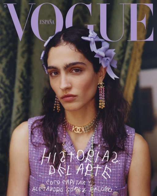 Vogue España cover featuring a portrait of a woman with dark hair wearing jewelry and a lilac tweed top, accessorized with floral hair clips.