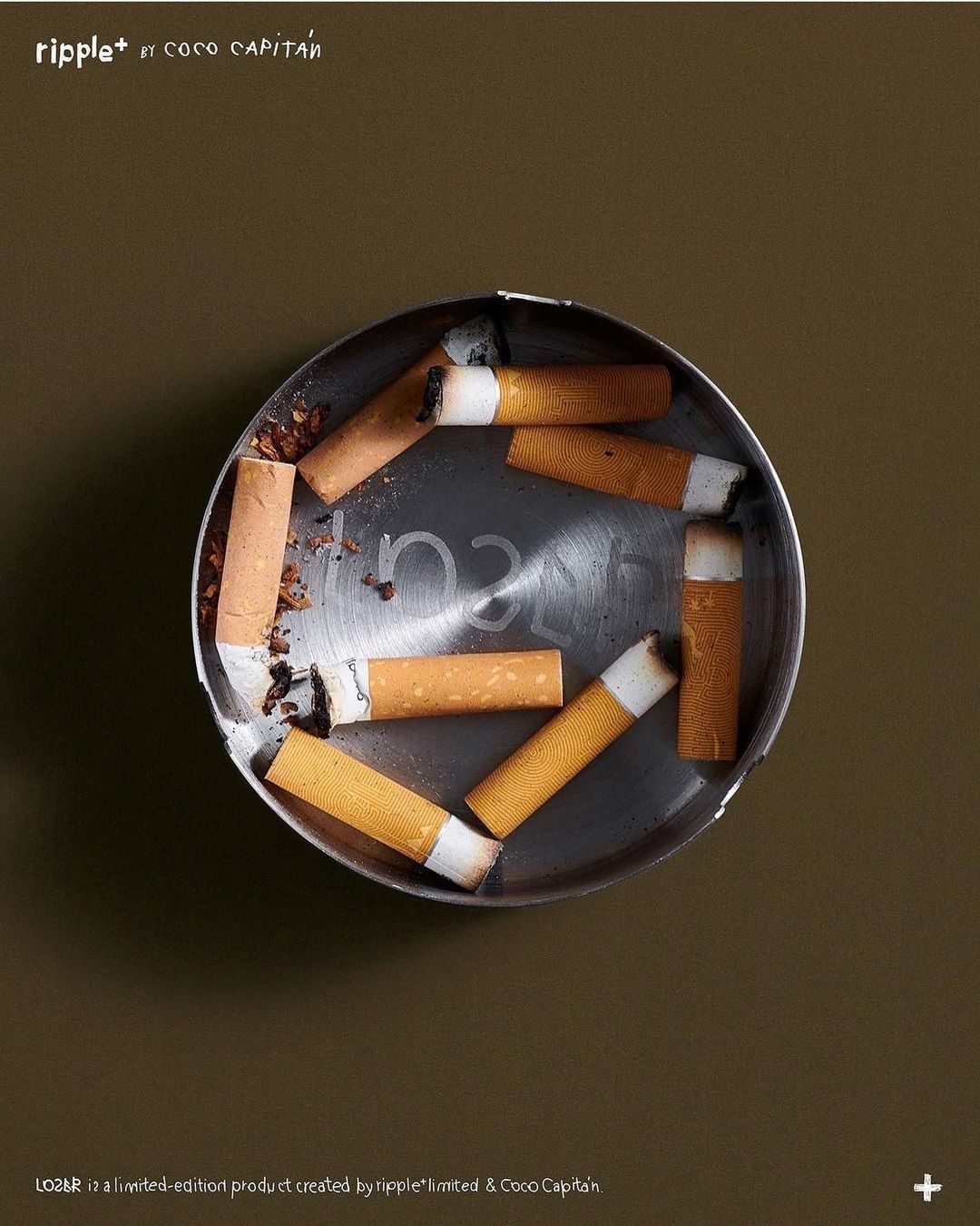 Overhead shot of cigarette butts in a metallic ashtray, set against a solid brown background, creating a still life composition.