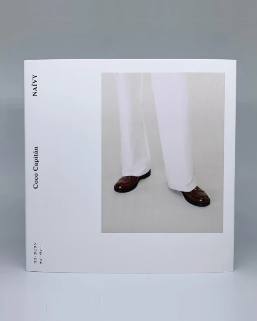 Fashion editorial featuring white trousers and brown leather shoes, set against a neutral backdrop, showcasing minimalist style.