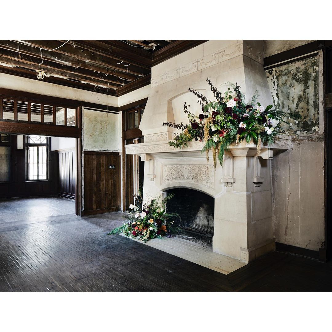Indoor view of a grand fireplace adorned with floral arrangements, highlighting interior architecture and floral design in a historic building.
