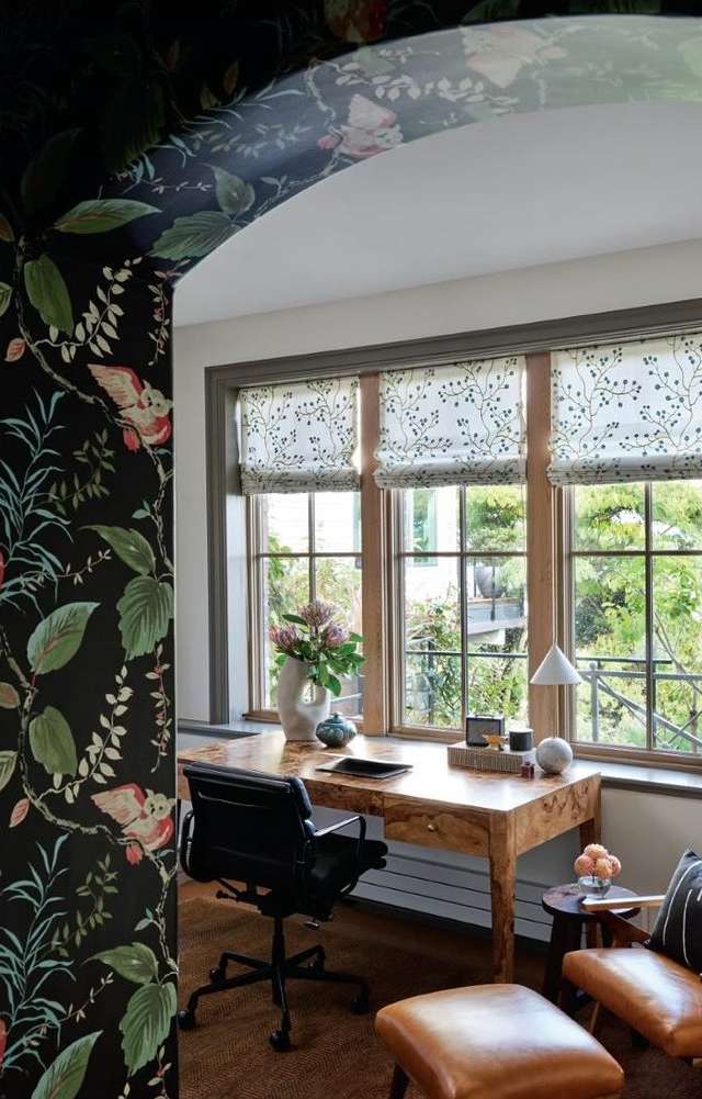 Home office area features a wooden desk, black office chair, decorative vases, and a patterned wall and window coverings.