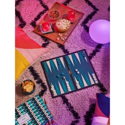 Overhead view of a backgammon board set up on a fluffy white rug with snack trays and pillows, photographed by Cody Ulrich.