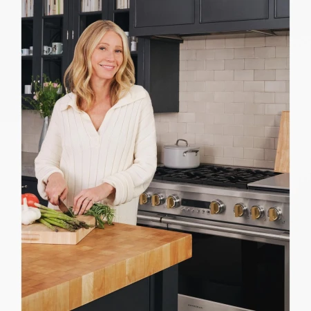 Gwyneth Paltrow chopping asparagus on a wooden kitchen counter in a modern kitchen photographed by Cody Ulrich.