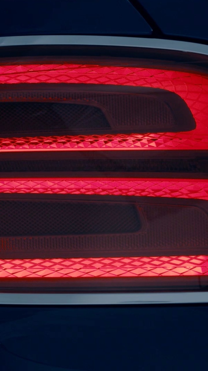 Close-up of the rear tail light of a dark blue automobile with red illuminated light bars.