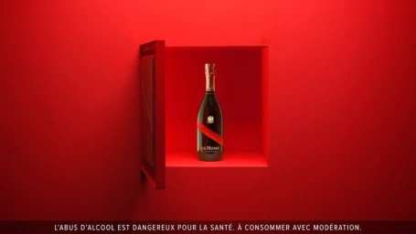 Champagne bottle displayed inside a red recessed wall niche with a partially open door against a monochromatic red background