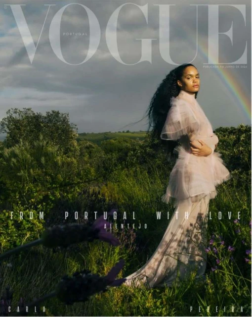 Vogue Portugal cover features a woman in a flowing dress standing in a field with a rainbow in the background, artistic fashion portrait.