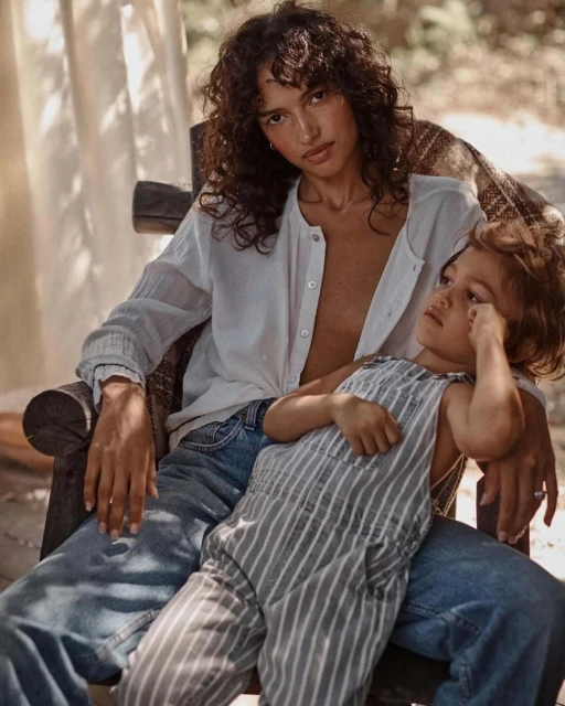Woman and child on chair in outdoor setting, soft natural light, casual clothing, intimate pose, promoting a cozy, family-oriented lifestyle.