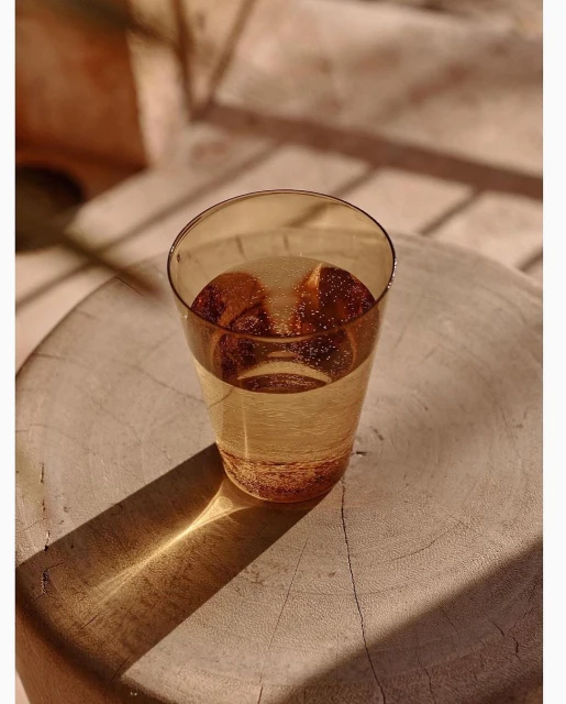 Close-up of a glass of sparkling water on a wooden surface, with sunlight and shadows creating a warm, natural ambiance. Refreshing drink.