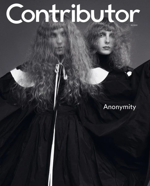 Fashion magazine cover features two adult women with big hair, wearing dark dresses with white trim against a gray background.
