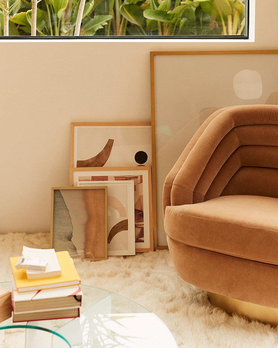 Interior decor featuring a modern armchair, framed wall art, glass coffee table with books, and a soft, textured rug.