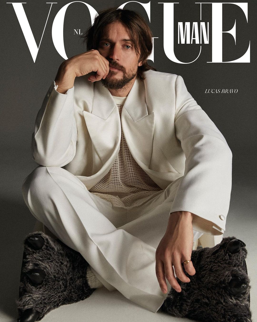 Magazine cover features a male model wearing a white suit and slippers, seated against a gray background with 'Vogue Man' text.