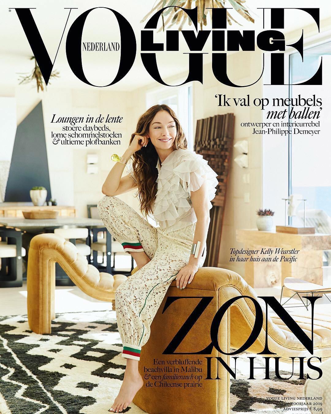Magazine cover featuring a seated woman, wearing patterned pants and a ruffled top, posing on a tan chair in a stylish interior setting.