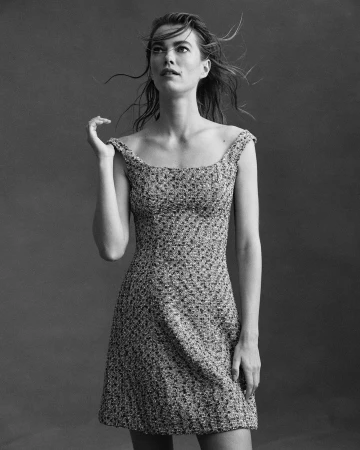 Monochrome portrait of a woman in a patterned dress with windblown hair against a dark studio background by Coliena Rentmeester.