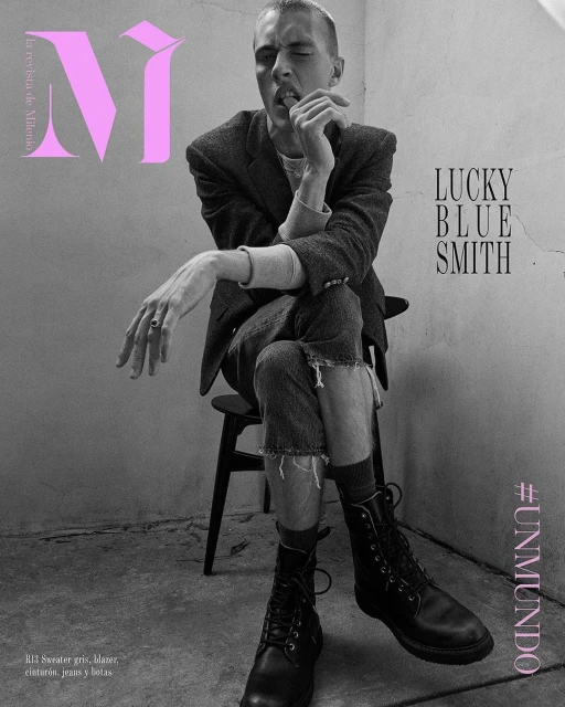 Black and white magazine cover photo features a young man in a suit and boots, seated against a textured wall, with magazine text.