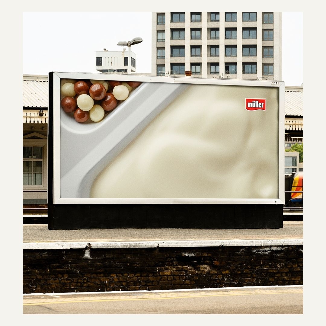 Outdoor billboard displays a Müller yogurt advertisement with chocolate and white chocolate balls against a building backdrop.