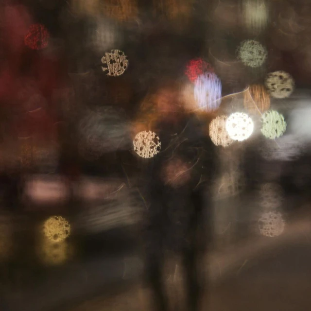 Abstract urban scene featuring blurred figures and bokeh lights at night, creating an atmospheric street photography image.