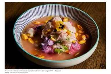 Close-up of Peruvian ceviche in a patterned ceramic bowl garnished with edible flowers and toasted corn kernels