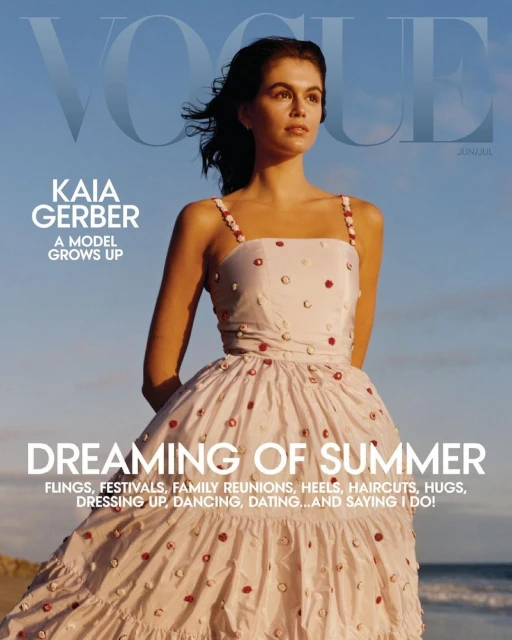 Vogue cover featuring Kaia Gerber in a white dress with red embellishments, set against a blue sky and sandy beach.