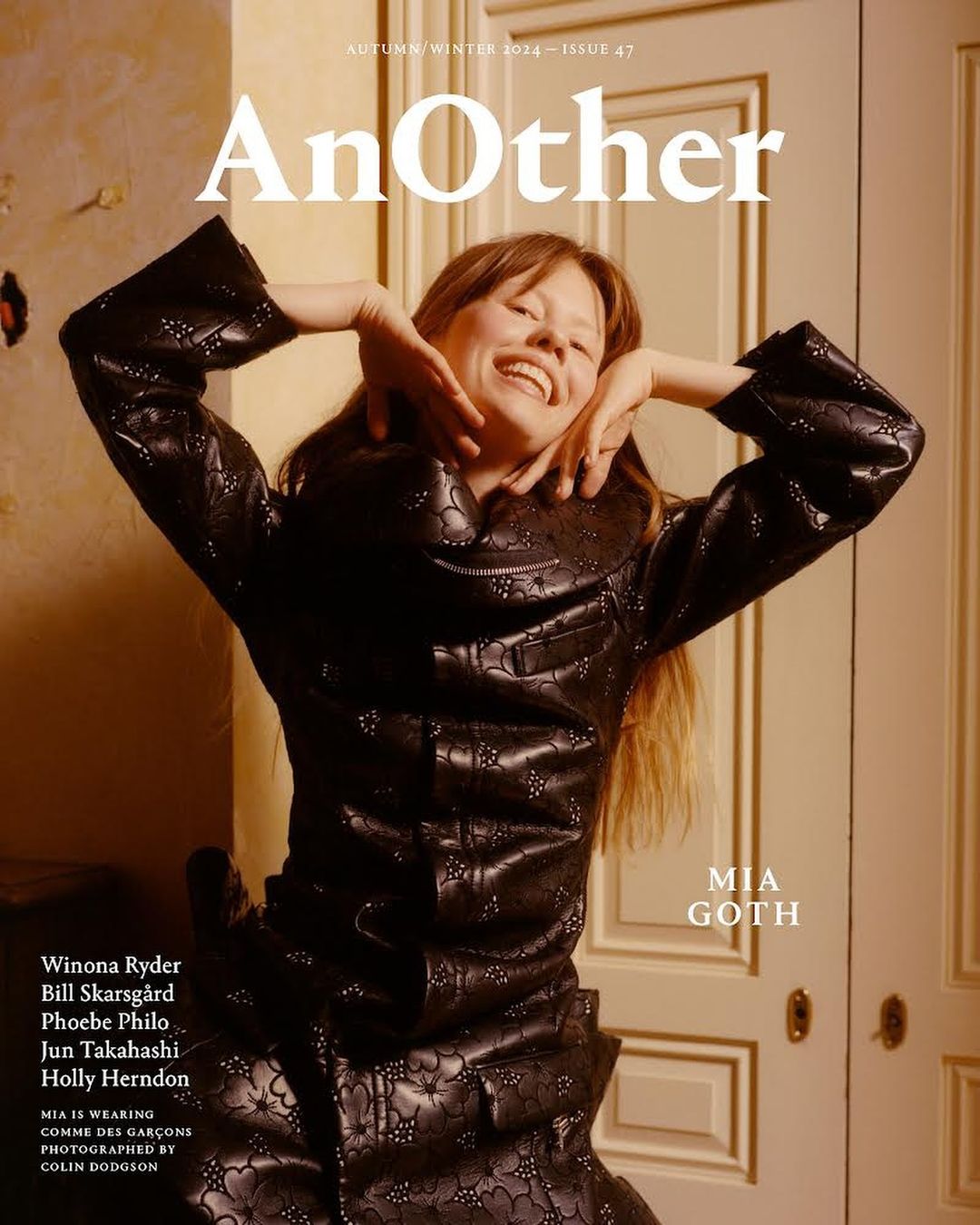 Mia Goth on the cover of AnOther Magazine Autumn/Winter 2014, Issue 47, wearing Comme des Garçons, with a warm smile, indoors.