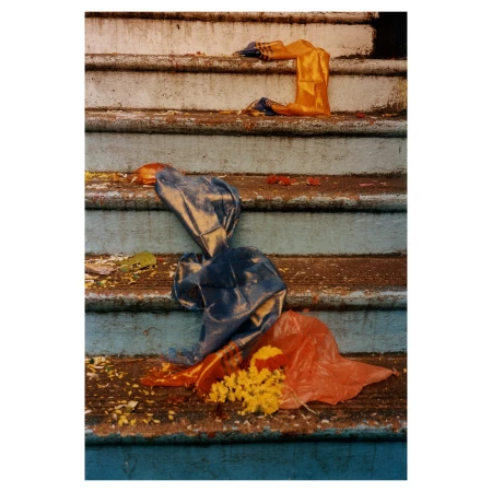 Discarded colorful plastic bags and yellow flower petals litter the weathered concrete steps of an outdoor staircase with chipped paint.