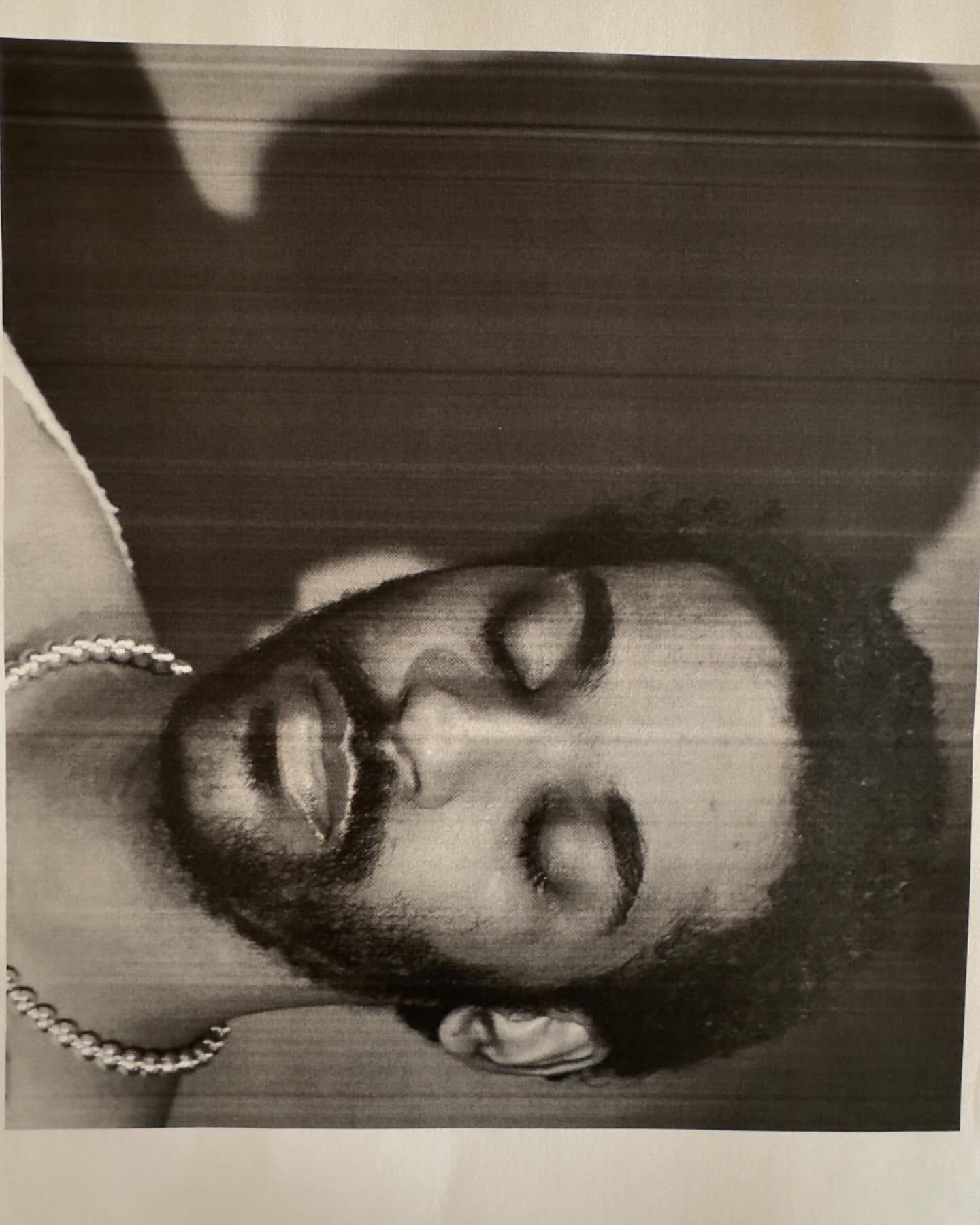 Monochrome portrait of a man with eyes closed wearing a thick metallic chain necklace by photographer Collier Schorr.