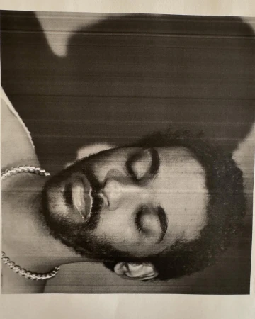 Monochrome portrait of a man with eyes closed wearing a thick metallic chain necklace by photographer Collier Schorr.