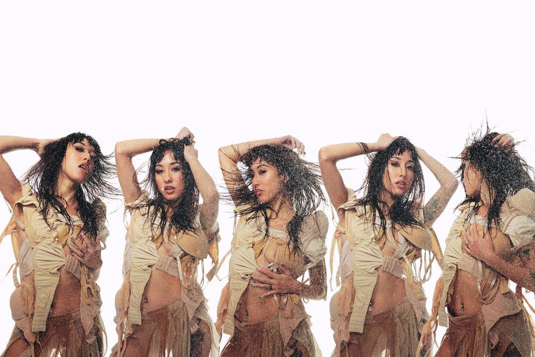 Multiple exposures of an Asian woman in a tan, fringed outfit, under water. The backdrop is bright white, with water droplets visible.
