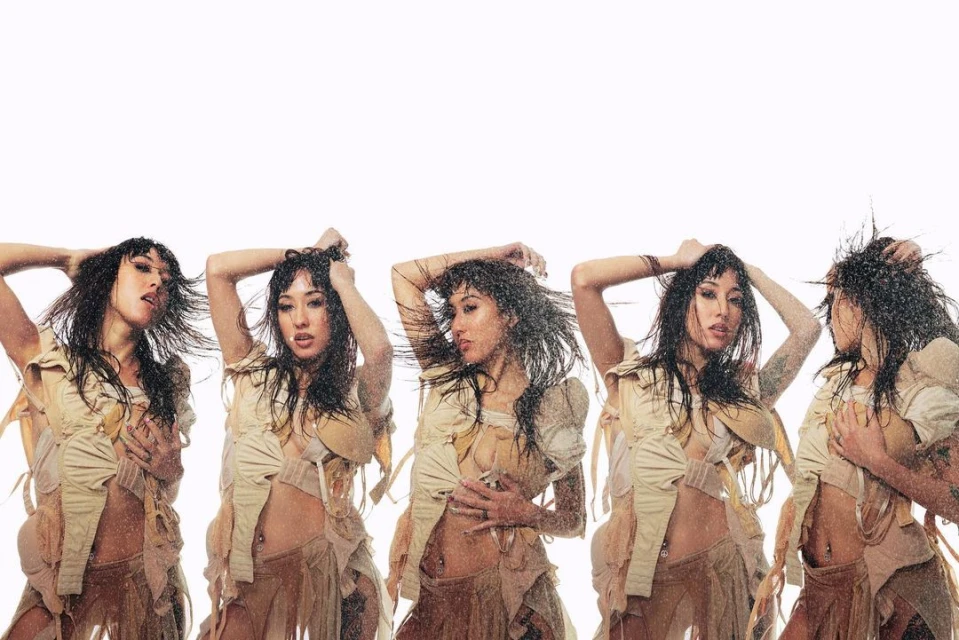 Multiple exposures of an Asian woman in a tan, fringed outfit, under water. The backdrop is bright white, with water droplets visible.