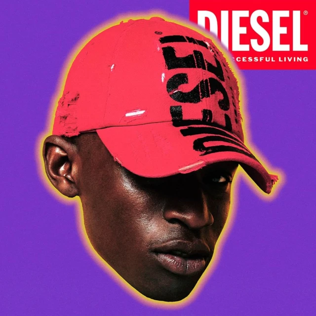 African-American man with close-cut hair wears red baseball cap with a black logo against a purple background with a brand logo.