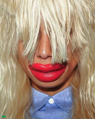 Close-up of a person with platinum blonde hair partially obscuring their face, featuring prominent red lips and a blue collared shirt.