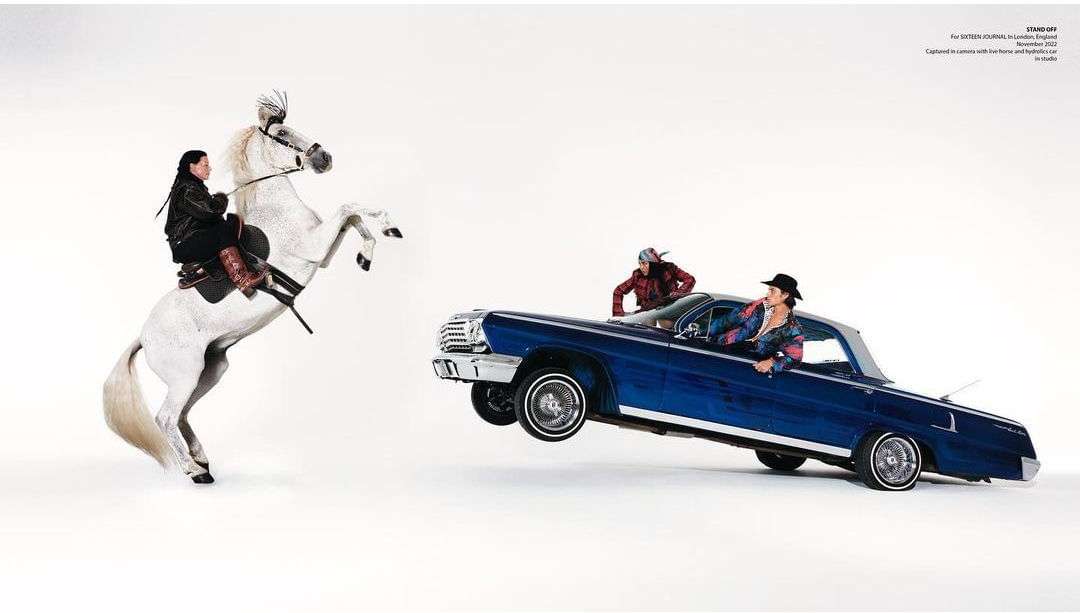 A striking photo captures two people in a lowrider car and a woman on a rearing white horse against a stark white background.