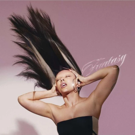 Woman in black top with dark hair tossed upward against a pink backdrop by Conor Cunningham