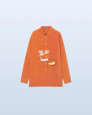 Still life: an orange button-down shirt with a glass of water and a slice of citrus fruit against a light blue backdrop.