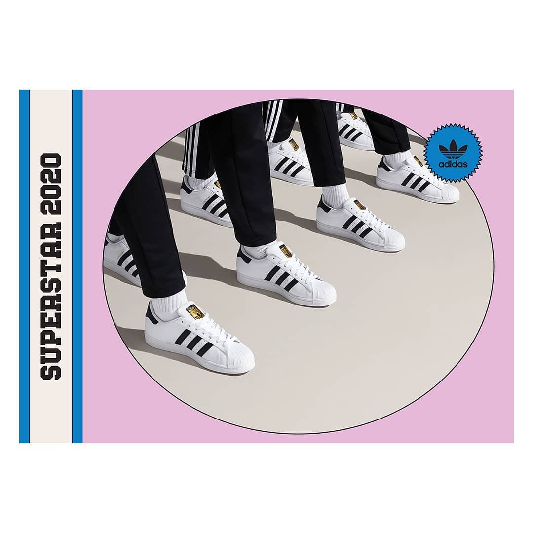 Several pairs of Adidas Superstar sneakers are displayed in a minimalist presentation with a pink background and black stripe accents.