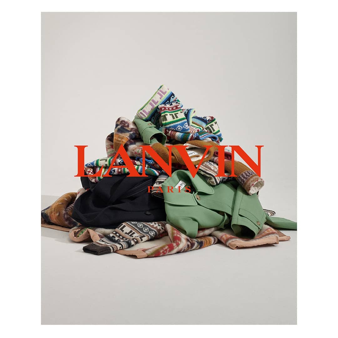 Pile of colorful Lanvin sweaters and jackets on a white background with the Lanvin logo. Fashion editorial with clothing.