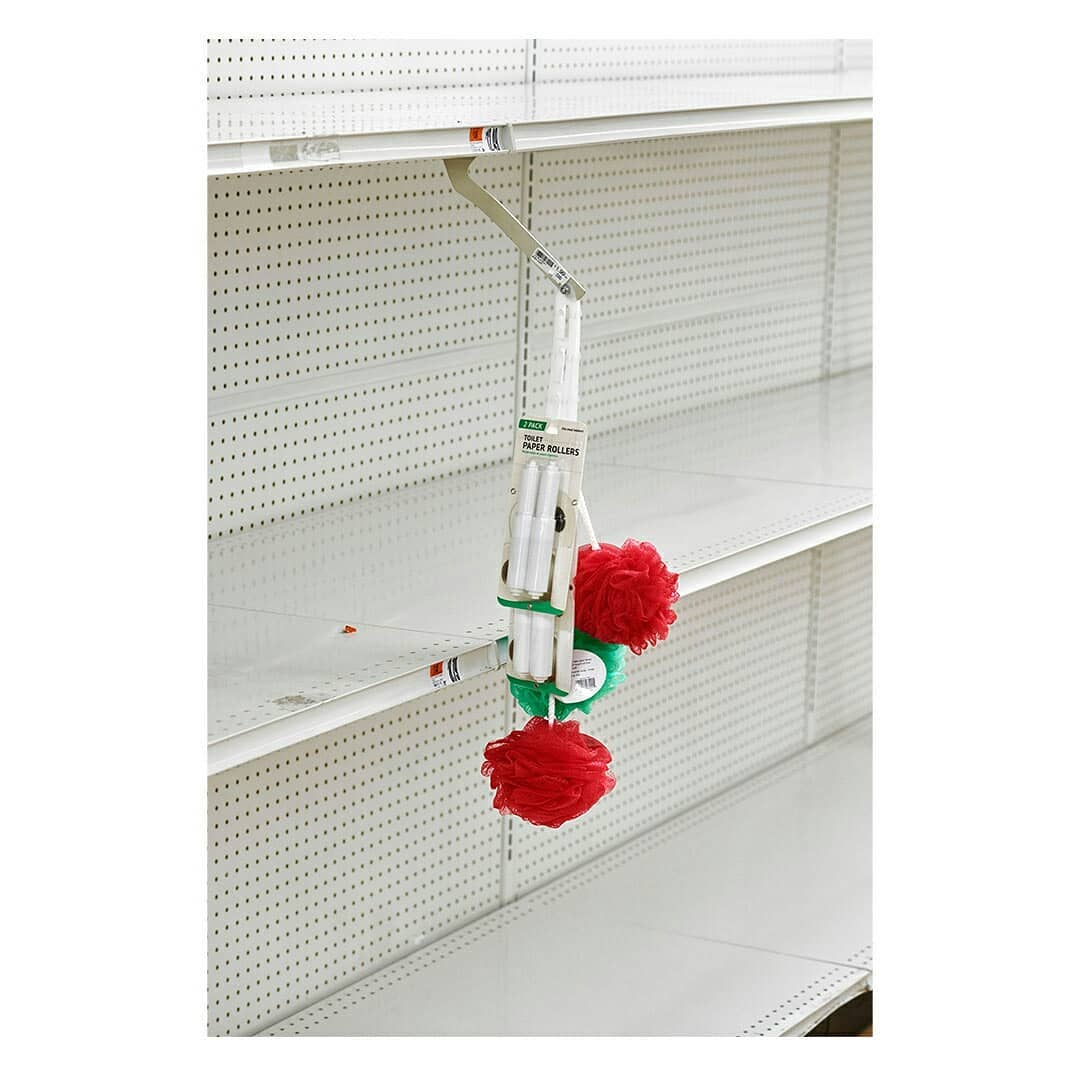 Retail display of hair rollers, showing white rollers wrapped in green bands and topped with red, textured balls hanging on a metal rack.