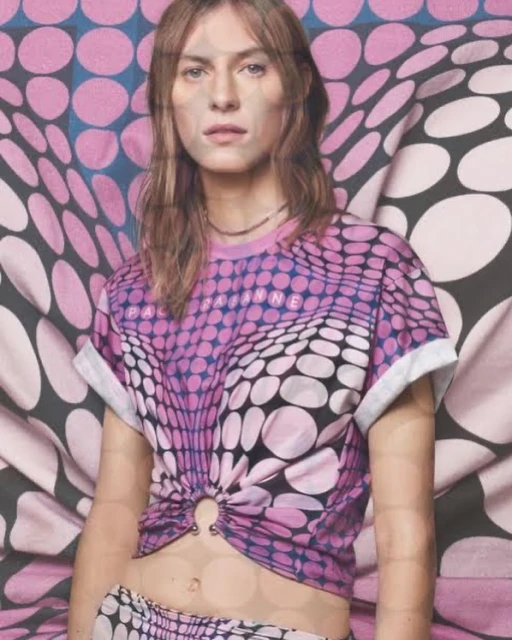 Young woman poses in a polka-dot patterned shirt and skirt, indoor studio setting with draped textile background featuring similar patterns.