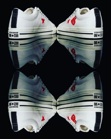Two pairs of Converse One Star Comme des Garçons sneakers mirrored against a black background, showcasing their unique design.