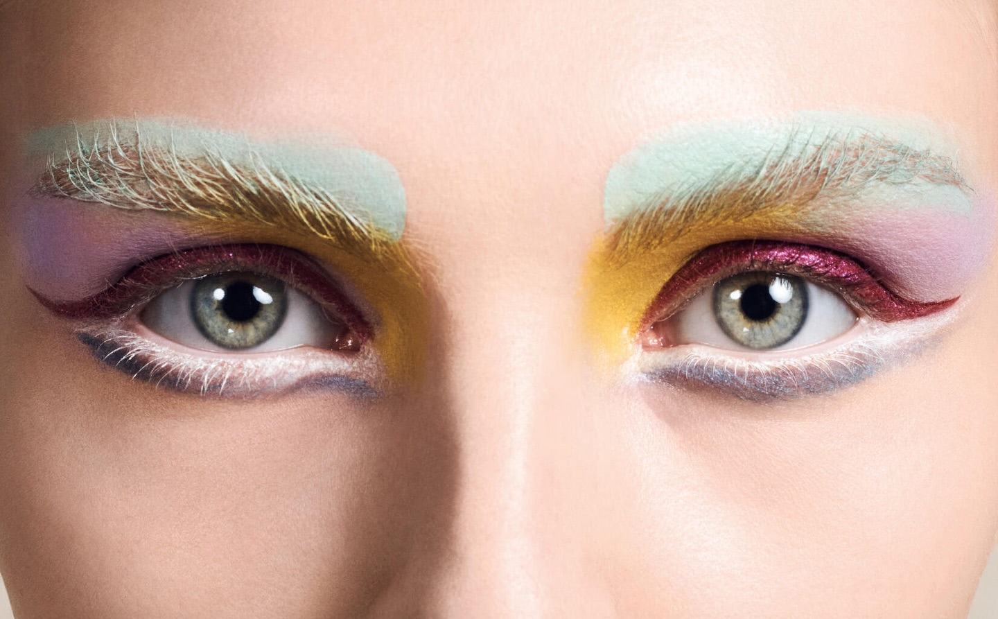 Close up portrait of a person's eyes featuring elaborate pastel eyeshadow and bleached painted eyebrows by Craig McDean.