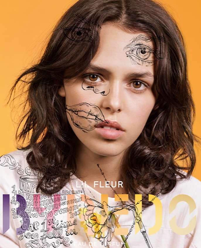 Artistic portrait of a brunette female with line-art face drawings, wearing a printed top on an orange background. Fashion concept.