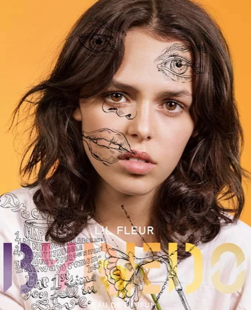 Artistic portrait of a brunette female with line-art face drawings, wearing a printed top on an orange background. Fashion concept.