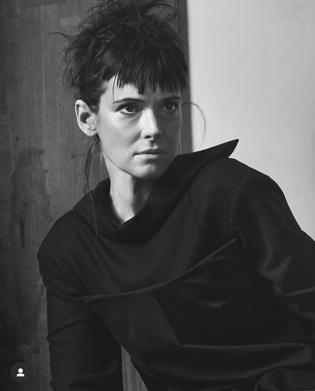 Black and white portrait of a woman with dark hair and fringe wearing a black top by Craig McDean.