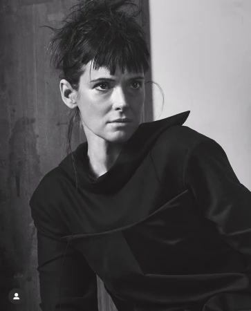 Black and white portrait of a woman with dark hair and fringe wearing a black top by Craig McDean.