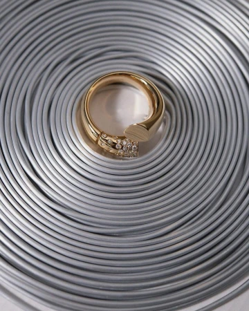 Close-up of a gold ring with diamond accents on a textured silver coiled metal background. Elegant jewelry shot for fashion or retail.