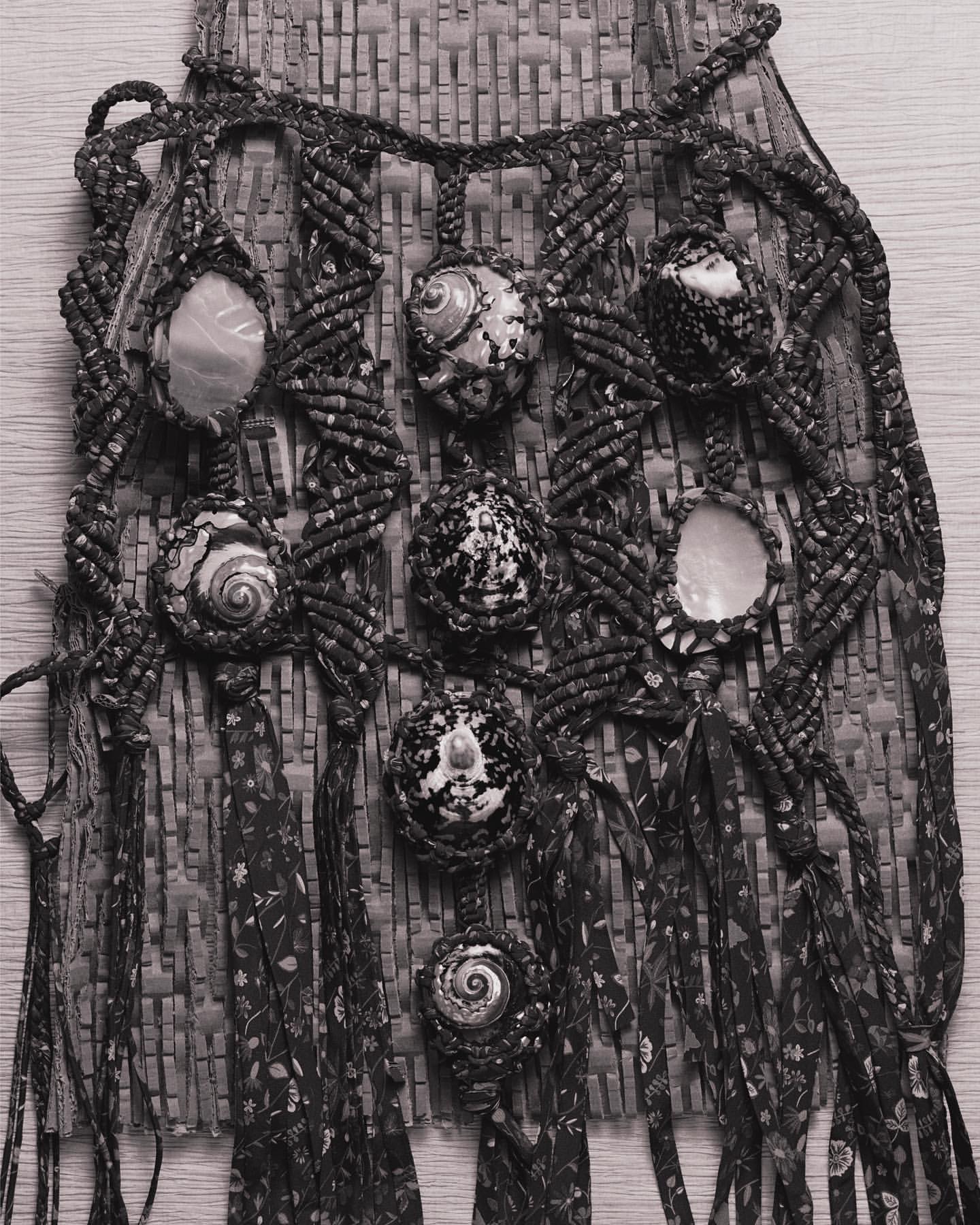 Handmade macrame wall hanging with seashells and woven textile, creating an artistic bohemian-style decor piece.