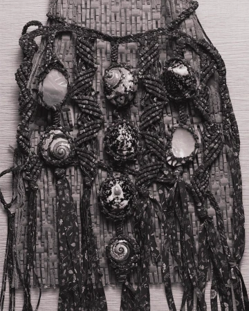 Handmade macrame wall hanging with seashells and woven textile, creating an artistic bohemian-style decor piece.