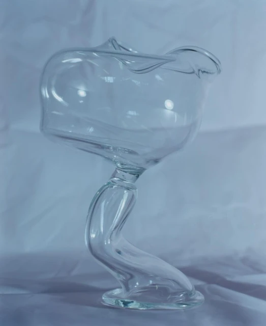 Elegant clear glass vase with a twisted stem on a white surface, showcasing modern design and translucent material in soft lighting.