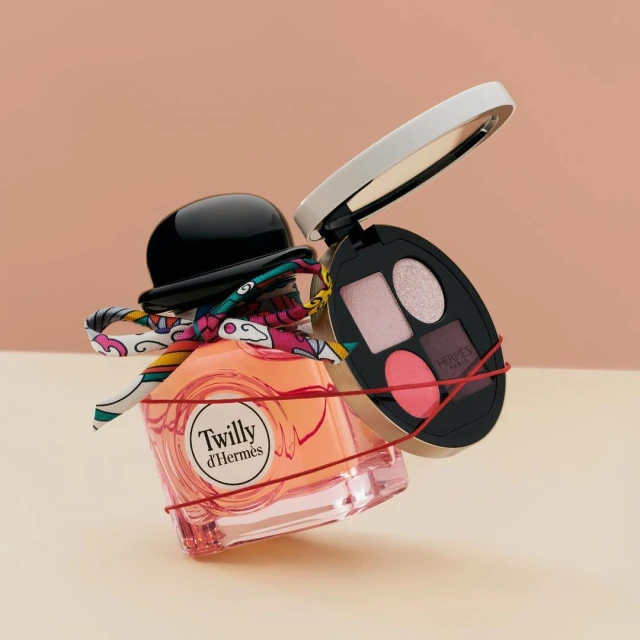 Still life shot of Twilly d'Hermès perfume bottle with a colorful scarf and red string, paired with an eye shadow palette in a studio setting.