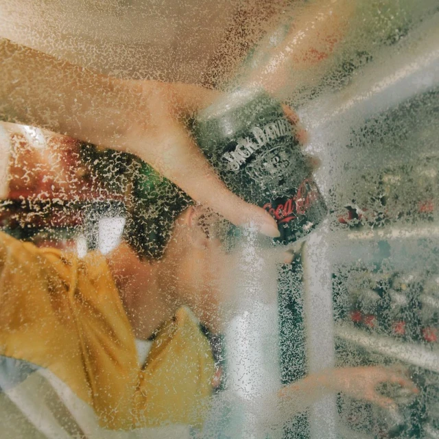 Close-up shot of a person's hand reaching into a beverage refrigerator to grab a can of Jack Daniel's and Coca-Cola mix.