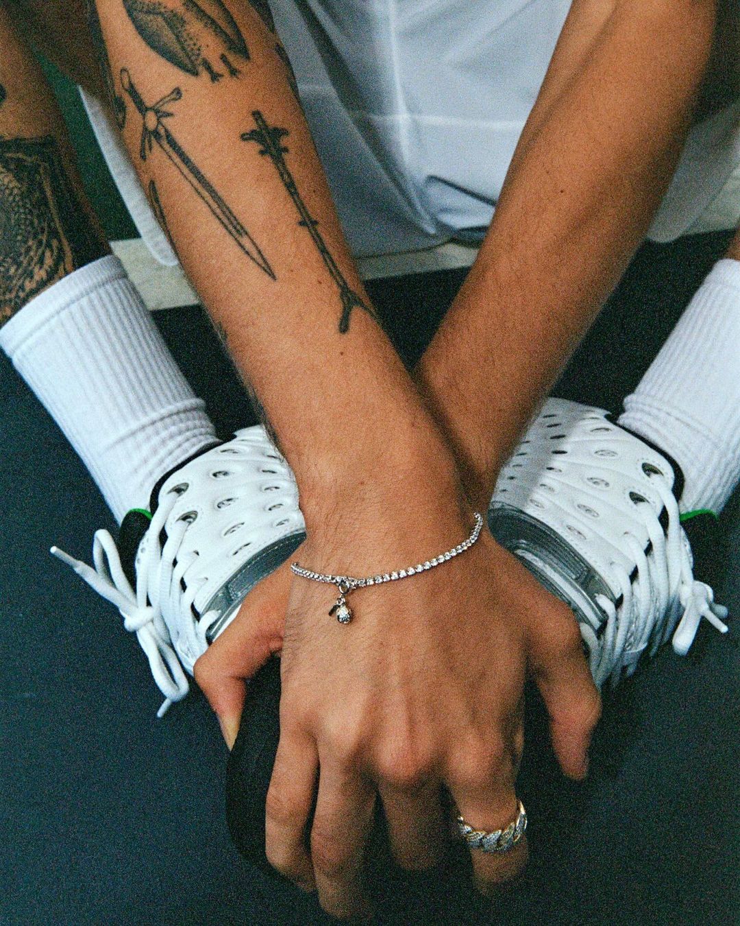 Close-up of a light-skinned adult male's hands wearing a diamond tennis bracelet and ring, holding a black bowling ball.